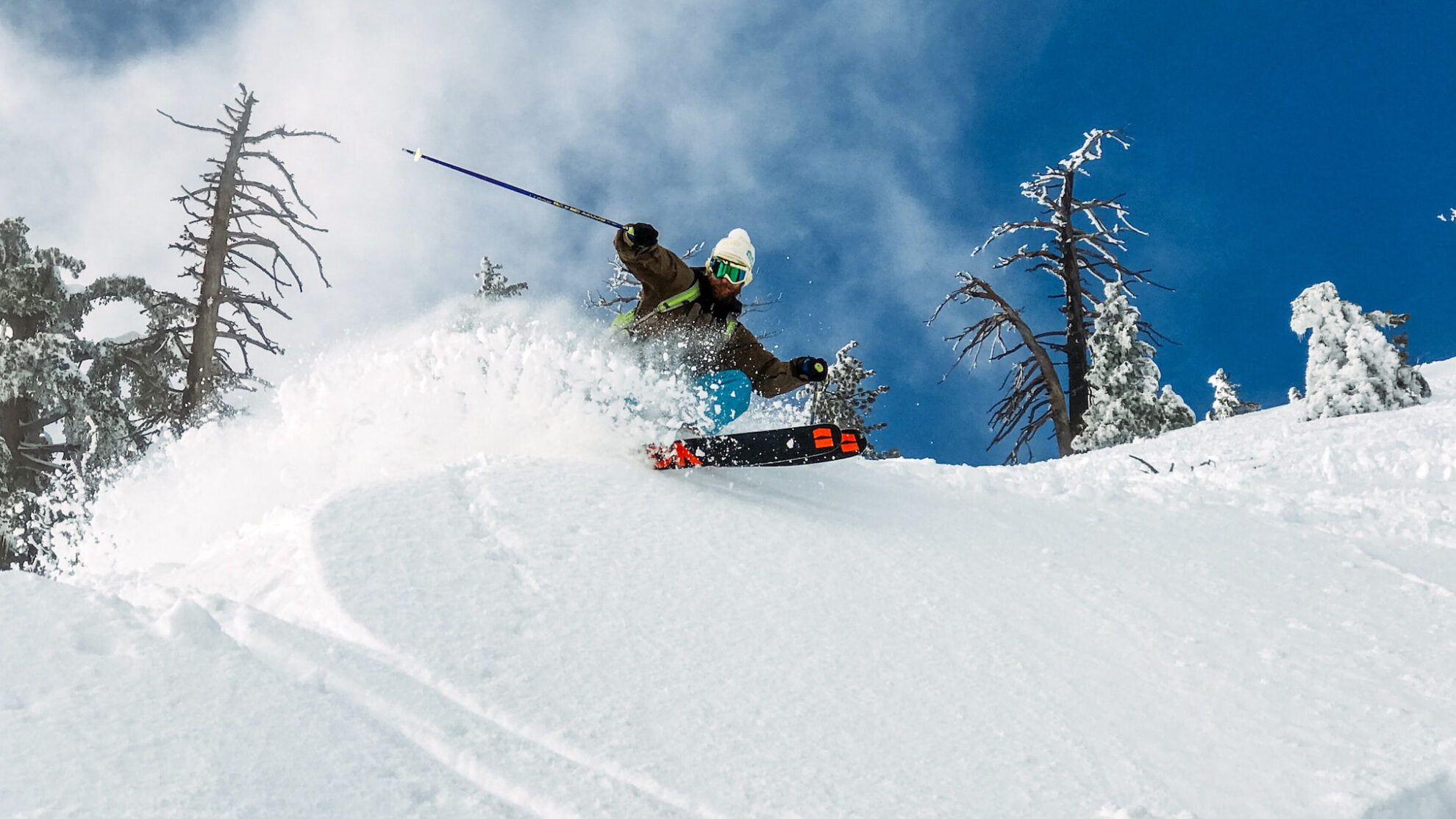 Skieur executant un virage dans de la poudreuse avec fond ciel bleu