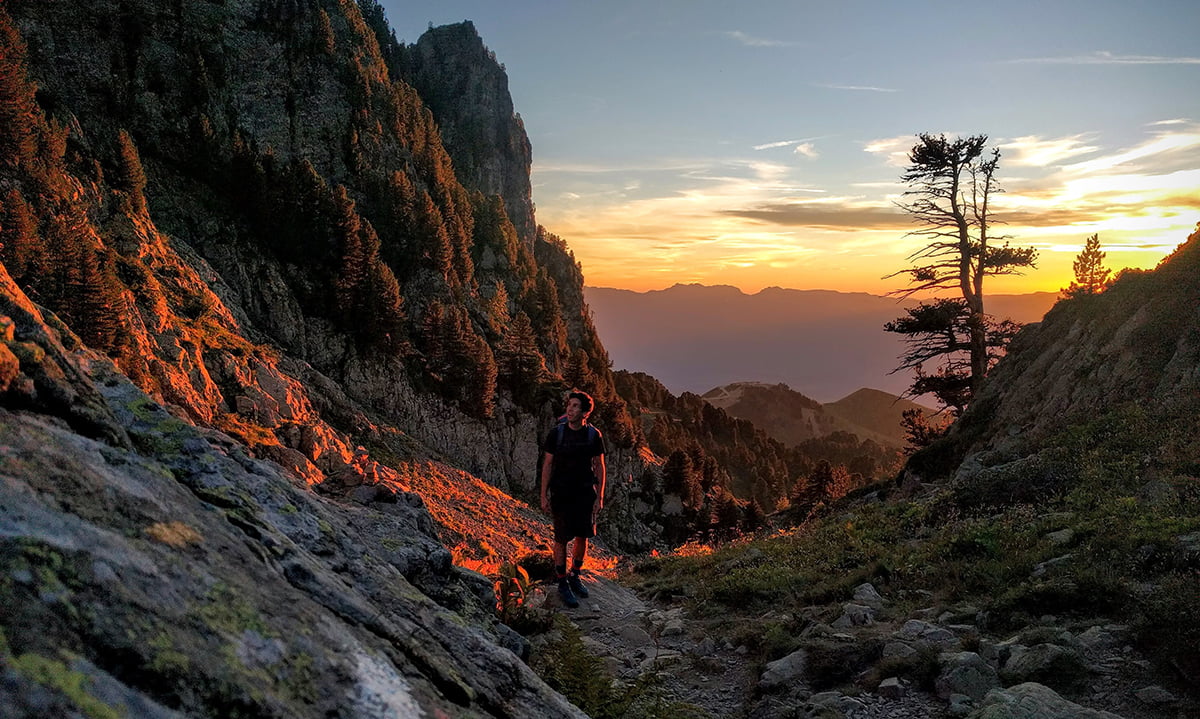 Montagnes éclairées par le coucher du soleil avec un randonneur sur un sentier
