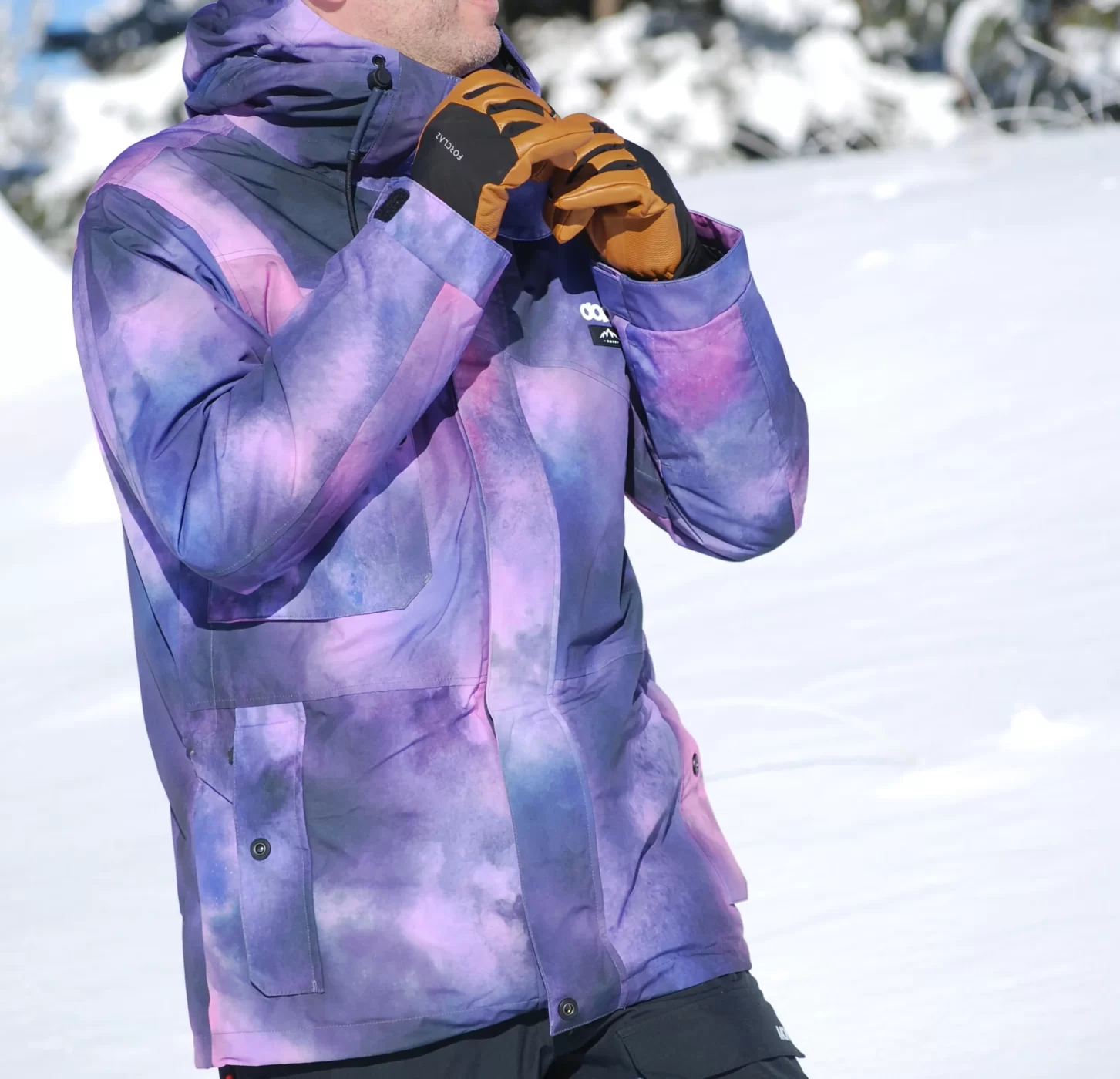 Le skieur porte la veste avec ces bras au niveau de la capuche.