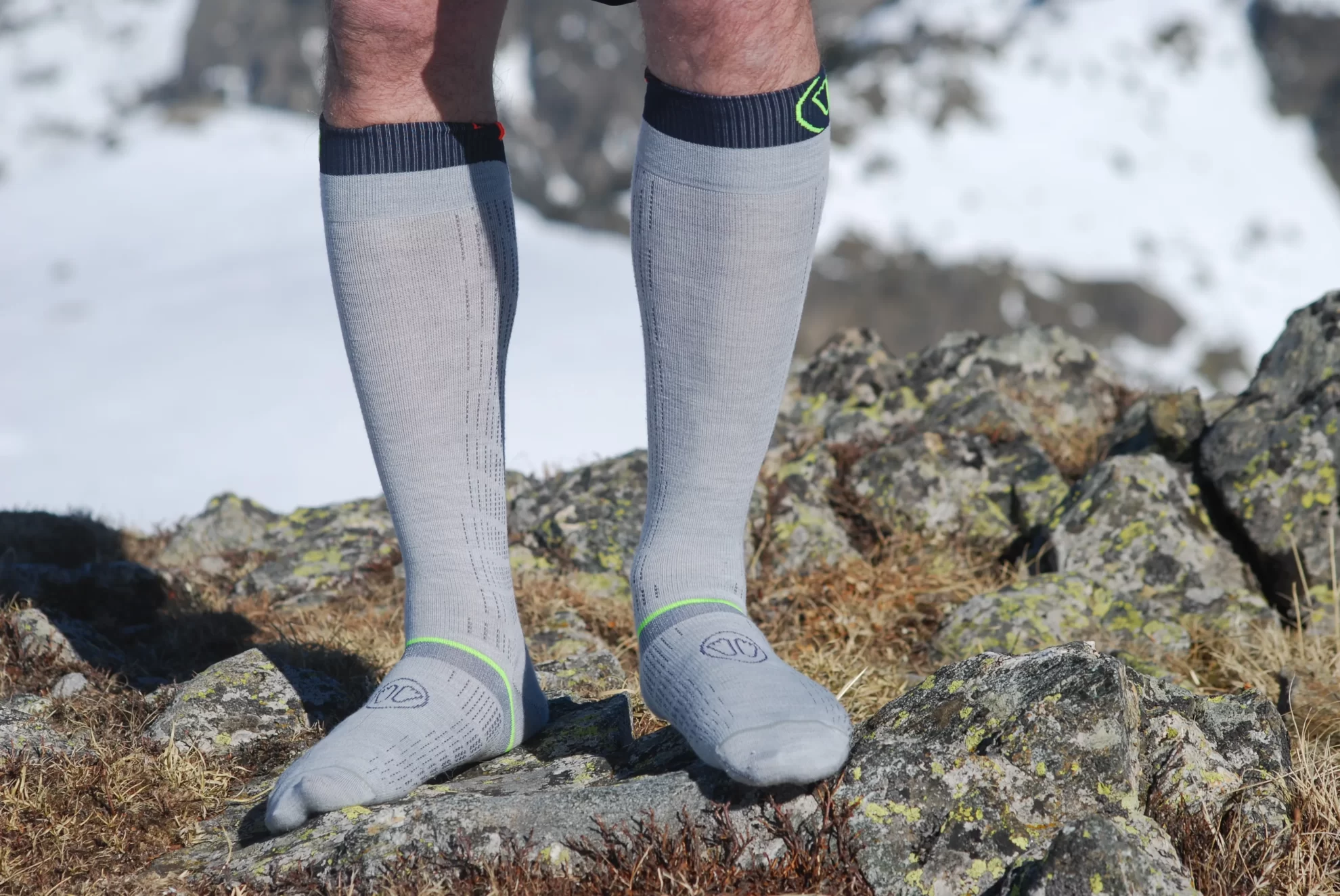 les deux chaussettes vues de face aux jambes d'un skieur sur des rochers.