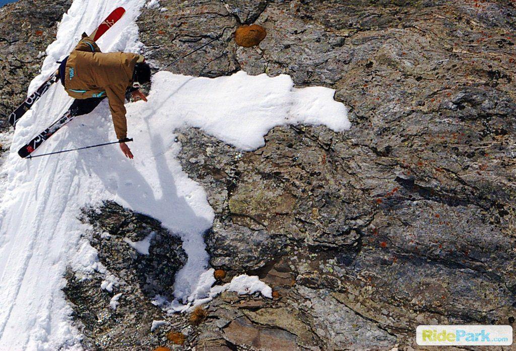 chute depuis un rocher à ski avec une petite langue de neige.
