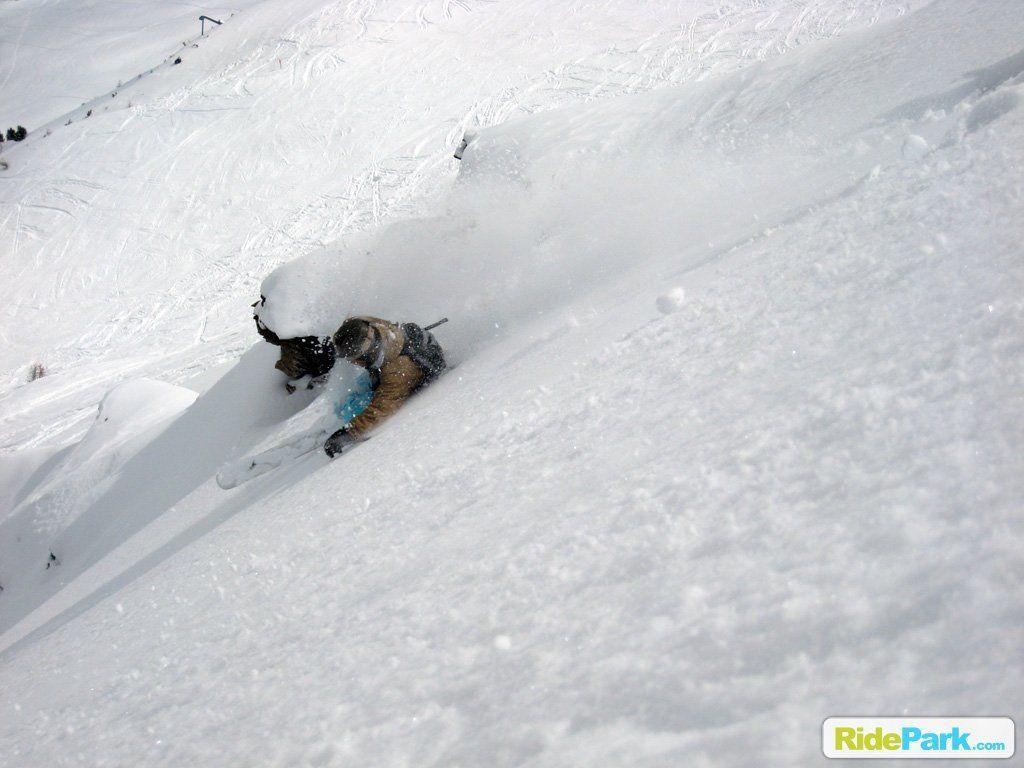 skieur en train de descendre une pente enneigée.