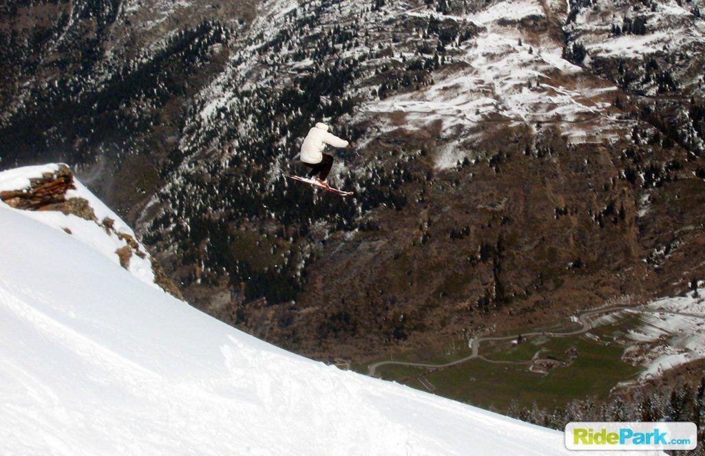 saut d'un rocher à ski, au fond la vallée en contre-bas est verdoyante.
