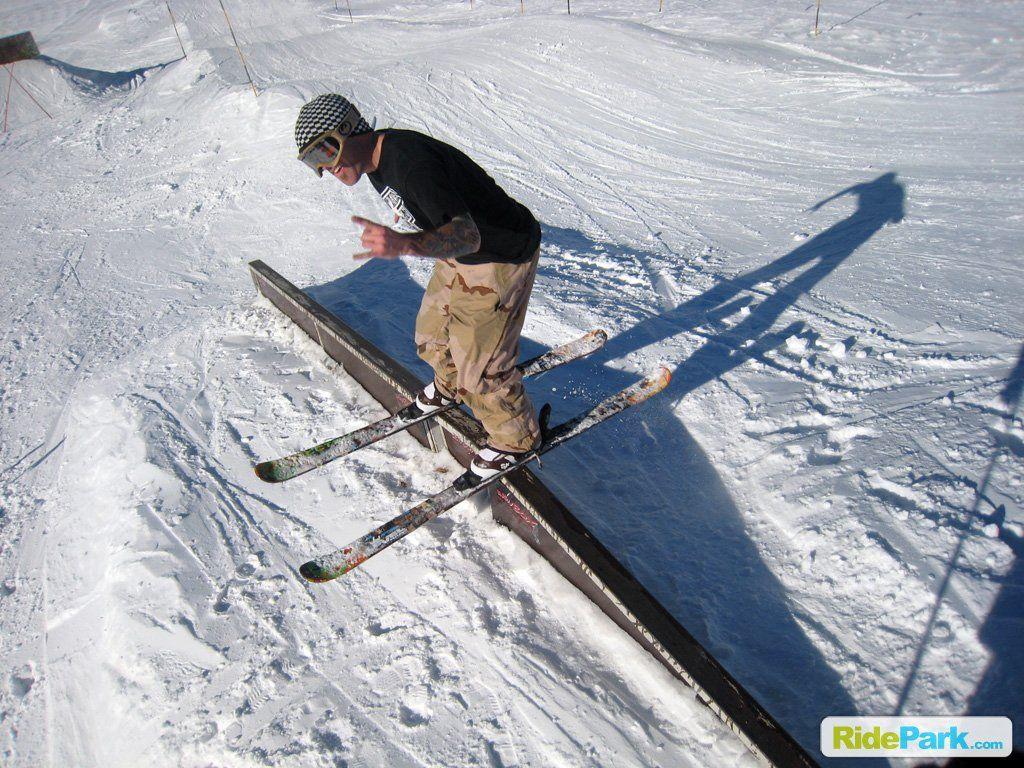 skieur sur un rail dans un snowpark.